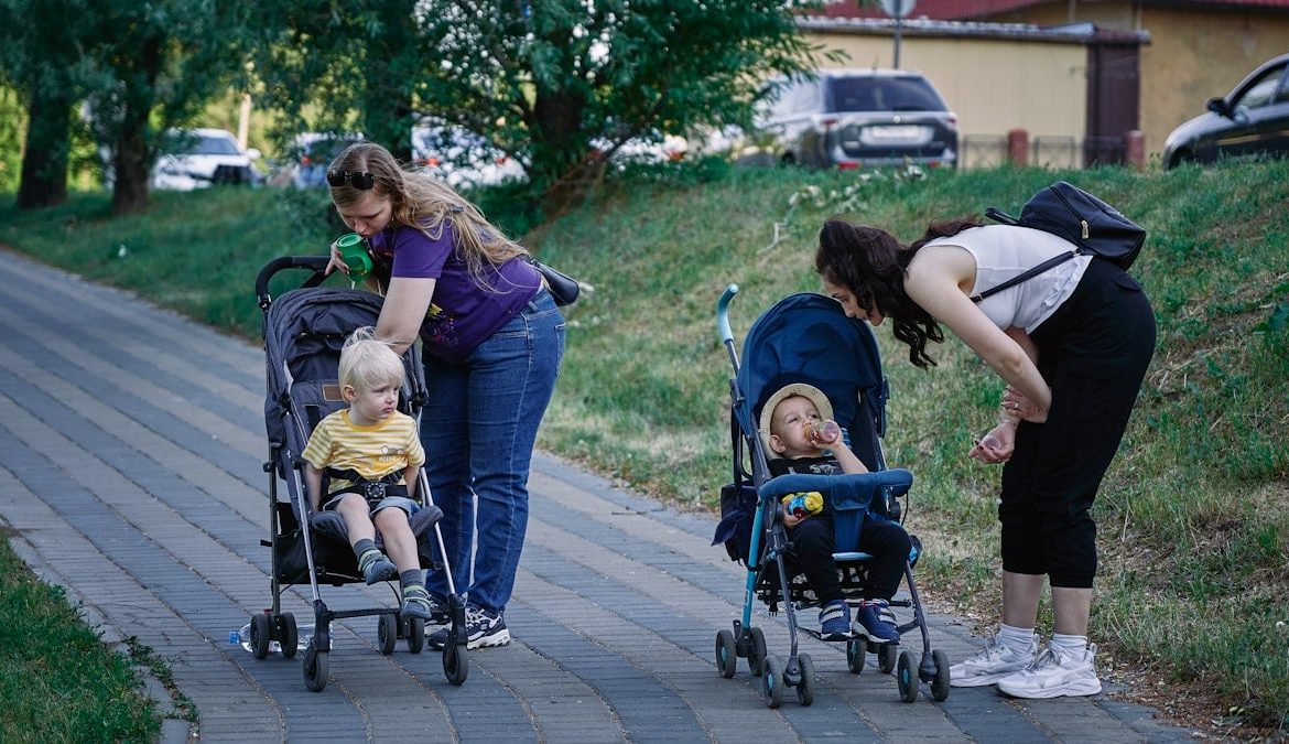 a woman pushing a stroller with two children in it